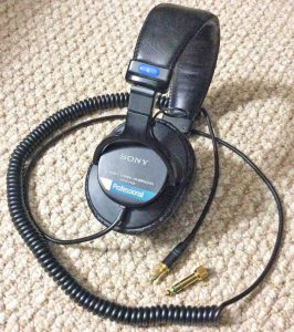 Picture of the Sony MDR-7506 Stereo Headphones, well used, showing the cable and the removable quarter-inch male gold-plated plug.