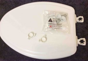 Picture of an Unwrapped New Toilet Seat, Showing Hardware and Installation Instructions Bag.