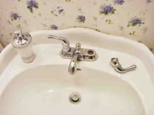 Picture of a broken bathroom sink faucet, in which the cold water valve abruptly came apart.