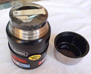 Picture of the Thermos food container with the lid Removed, showing the bowl side of the lid as well as the retractable stainless steel spoon. 