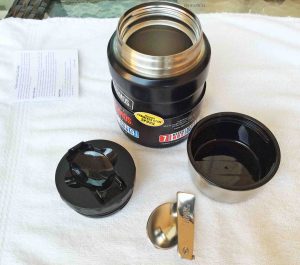 Picture of the Thermos Insulated 16 Ounce Food Jar Completely Disassembled, showing the outer lid, inner cap, spoon and the double walled storage container itself. 
