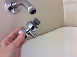 Picture of a holder for a hand held shower head, about to be screwed onto the supply pipe. 