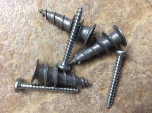 Picture of these metal drywall anchors with screws, laying loose.