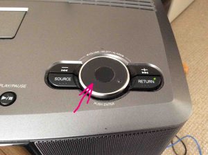 Picture of the Volume knob on the top of the radio, highlighted by the pink arrow.
