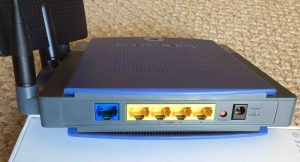 Picture of the back view of the Linksys WRT300N WiFi router. Rear view. Showing the antennas (left), wide area and local Ethernet ports, reset button, and power port.