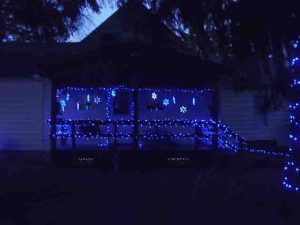 Picture of our LED Christmas light decorations outdoors, house south porch, showing lighted snowflakes, and small LED strings on porch railings and banisters. Outdoor Christmas Light Decorating Ideas.