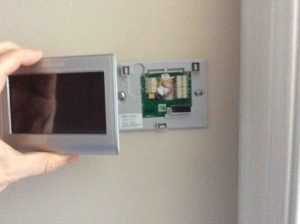 Picture of the Honeywell RTH9580WF Internet t-stat, being snapped onto wall plate.