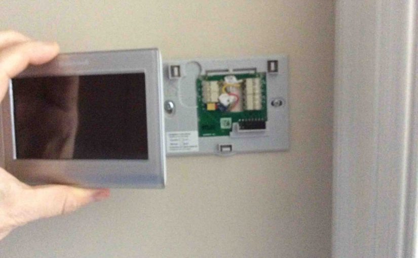Picture of the Honeywell RTH9580WF Internet Thermostat, being snapped onto wall plate.