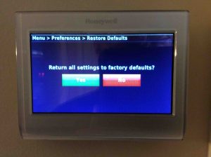 Picture of the Honeywell RTH9580WF touchscreen thermostat, showing the Restore Factory Defaults confirmation screen.