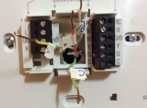 Picture of a Thermostat Wall Plate with wires labeled and disconnected.