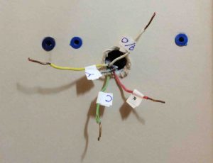 Picture of the wall behind a removed thermostat wall plate, showing the wires protruding. 
