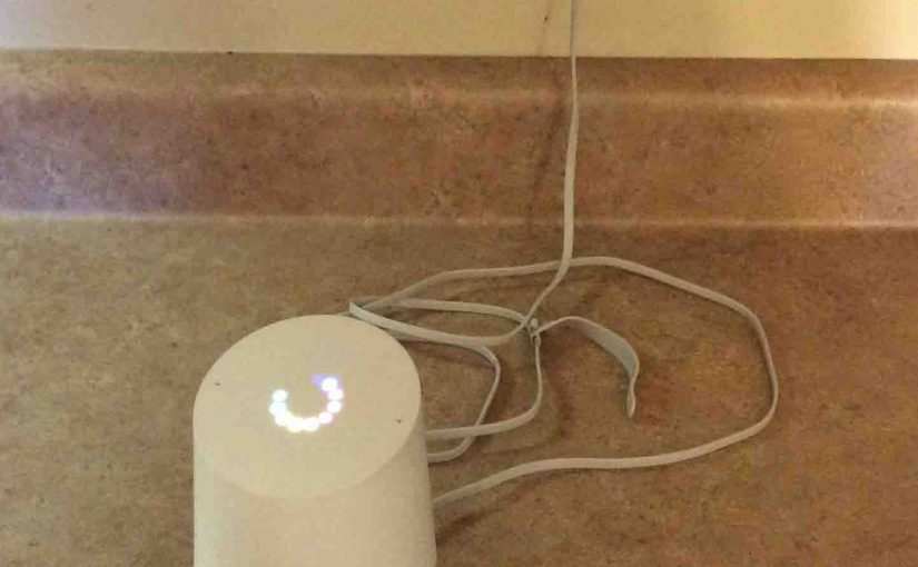 Picture of the Google Home Speaker powering up, showing multi-colored ring of lights on top, spinning and blinking during boot.