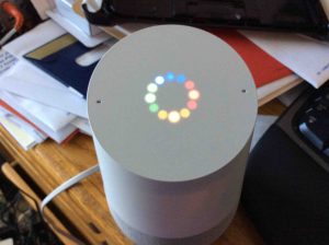 Picture of the Google Home speaker, booting in progress, displaying the multi colored light ring, indicating that. 