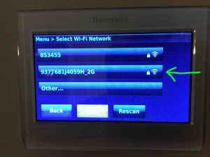 Picture of the Honeywell RTH9580WF thermostat, displaying the Select Wi-Fi Network screen, showing the wireless signal strength meter with a full strength signal.