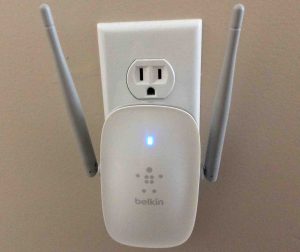 Picture of the Belkin F9K1122v1 range extender, operating normally, displaying solid blue light, front view.