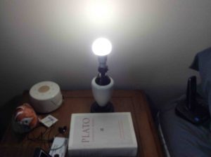 Picture of the Philips LED 100w A19 daylight white light bulb in bedroom lamp with shade removed, operating.