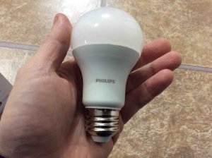 Picture of a Philips LED 75w A19 daylight white light bulb, held in hand.