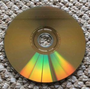 How to fix a DVD that skips and freezes. Picture of the Slightly dusty dual layer DVD disc, showing the gold data side