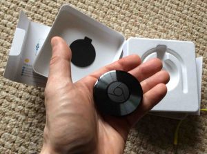 Picture of the Google Chromecast Audio receiver, held in hand.