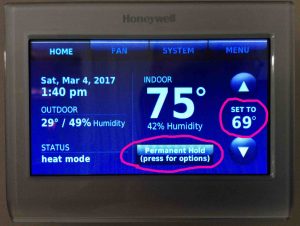 Picture of the thermostat, displaying its -Home- screen, with the new temperature of 69 degrees set, in -Permanent Hold- state.