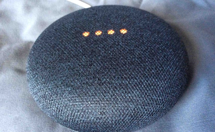 Picture of the Google Home Mini smart speaker, top front view, shown in muted mic mode.