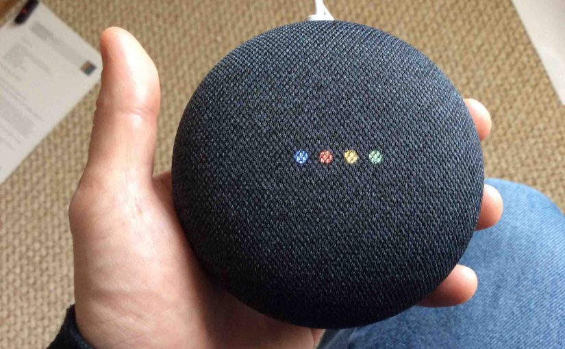 Picture of the Google Home Mini speaker, displaying multi colored lights during reboot.