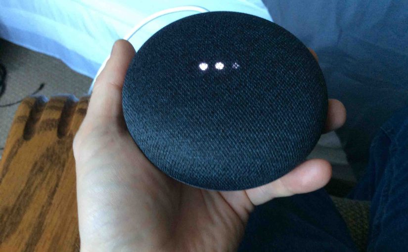 Picture of the Google Home Mini smart speaker, factory default reset in progress, showing scanning bright white lights.