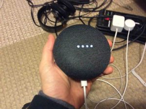 Picture of the Google Home Mini speaker, in setup mode, displaying the dimming white lights across the top.