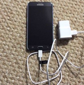 Front view picture of the smart phone, front view, with the wall charger connected. Unboxing Samsung Galaxy J7.
