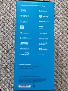 Picture of the Amazon Echo 2nd generation intelligent speaker box, side view, showing main streaming services list.