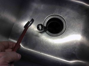 Picture of a garbage disposal, wrapping inserted wrench with another wrench, to loosen rusted blade drum. How to free up a stuck garbage disposal.