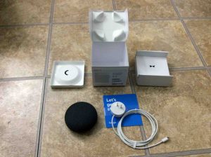 Picture of the Google Home Mini smart speaker, original box, and included accessories, completely unpacked.