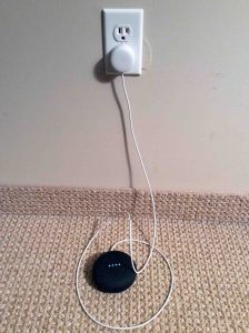 Picture of the Google Home Mini smart speaker, plugged into AC power and booting. 