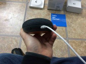 Picture of the rear view of the Google Home Mani smart speaker, showing the USB power cable inserted intot he USB power port on the speaker.