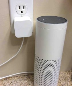 Picture of the Amazon Alexa Echo Gen 1 smart speaker with its AC power adapter plugged in.