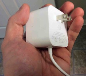 Picture of the AC power plug and cord, showing the wall part, held In hand.