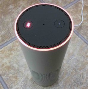 Picture of the Amazon Echo Gen 1 smart speaker, showing the Mic Mute Alexa feature as ON, Indicated by the red light ring and illuminated Mic Mute button.