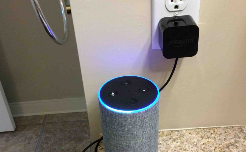 Picture of the Amazon Alexa Echo Gen 2 smart speaker with power adapter, plugged into wall outlet.