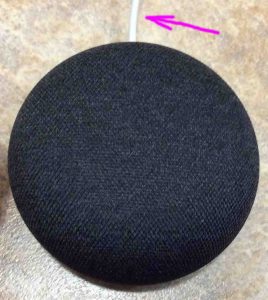 Top view of the Google Home Mini speaker, with the power cord at twelve o'clock.