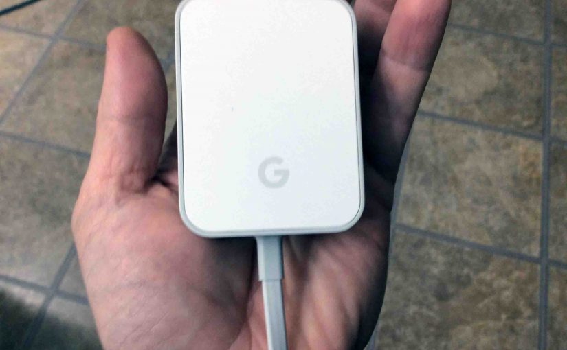 Picture of the Original Google Home smart speaker AC power adapter, held In hand, showing logo side.