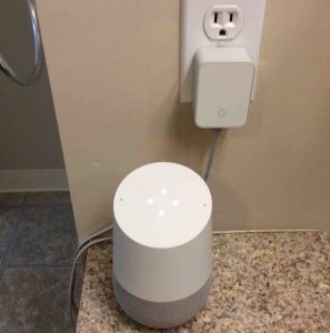 Picture of the Original Google Home smart speaker, during booting, along with AC power adapter plugged Into wall outlet.. How to Connect Google Home to Honeywell Thermostat.