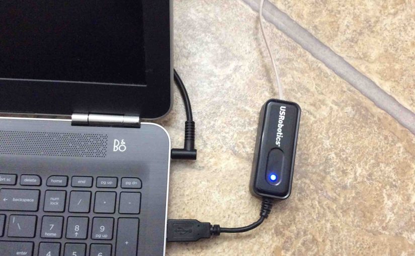 Picture of a US Robotics USB modem, connected and operating on laptop computer.