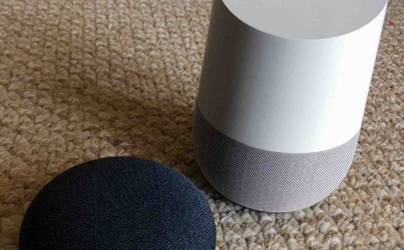 Picture of the Google Home Mini and Original smart speakers together, side by side, front view.