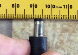 Picture of the Logitech AC adapter, model PSC30R-120, showing its DC output connector tip placed against a ruler.