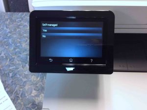 Picture of the HP Color Laserjet M477 printer, displaying its - Default Settings->Self Managed- confirmation screen.