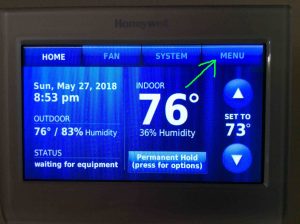 Picture of a common Honeywell smart WiFi thermostat, showing its -Home- screen, with the -Menu-button highlighted. How to Find Honeywell Thermostat MAC Address.