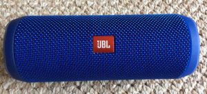 Picture of the JBL Flip 4 portable Bluetooth speaker, showing logo side, horizontal view.
