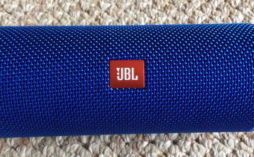 Picture of the JBL Flip 4 portable Bluetooth speaker, showing logo side, horizontal view.