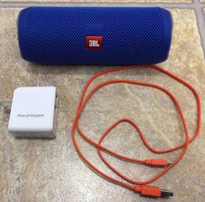 Picture of a common JBL speaker with a RavPower USB charger and micro USB charge cable.
