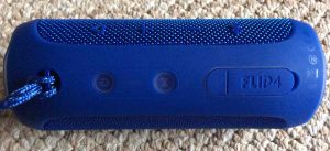 Picture of the JBL Flip 4 portable speaker, top view, showing speaker controls, showing the port door fully closed. 